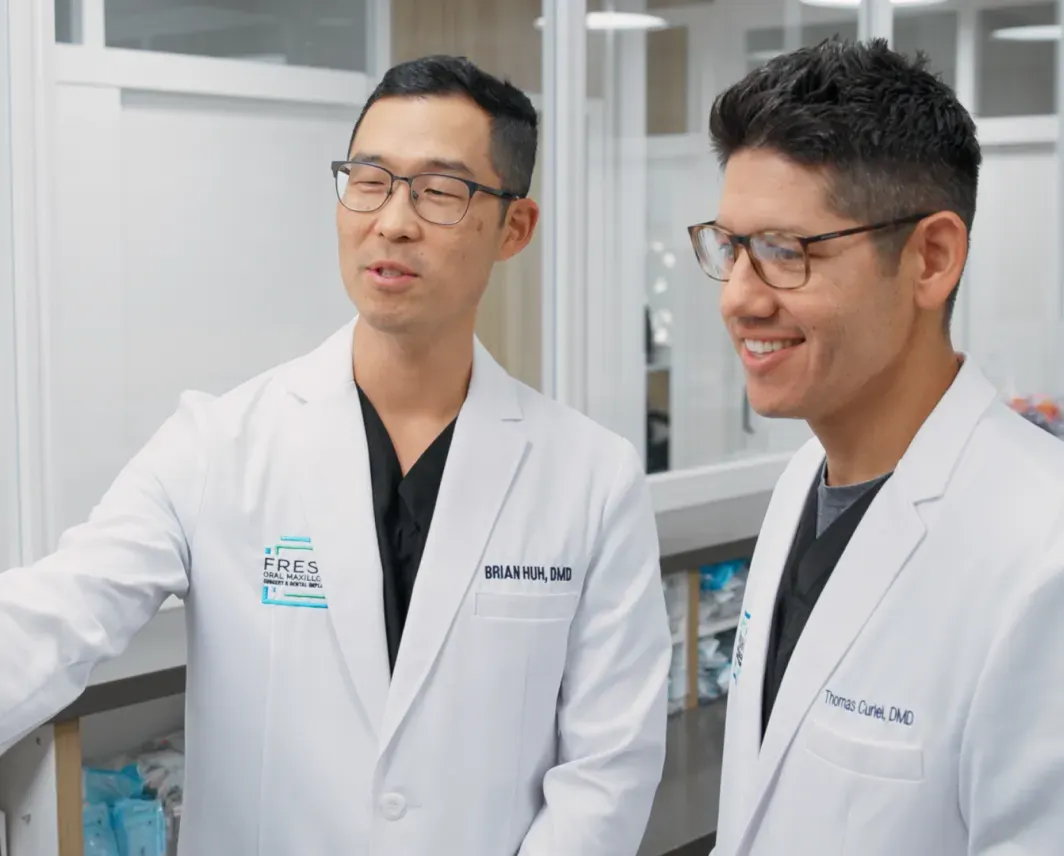 Dr. Brian Huh and Dr. Thomas Curiel in white coats, talking and smiling in the office